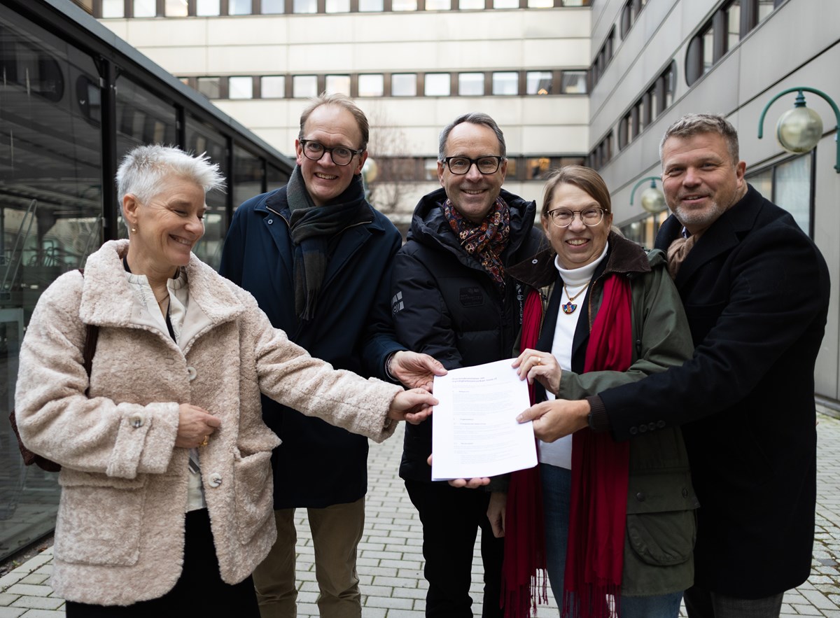 IT-chefer på fem myndigheter i Norrköping skriver på avtalet om myndighetssamverkan inom IT. Fem personer står utanför en byggnad. Alla håller i ett papper. De är glada.