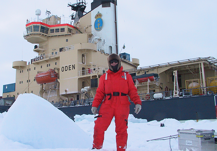 Pauline Snoeijs Leijonmalm framför Oden på en tidigare expedition. Foto: Katarina Abrahamsson Foto på Pauline framför isbrytaren Oden och snö runt omkring.