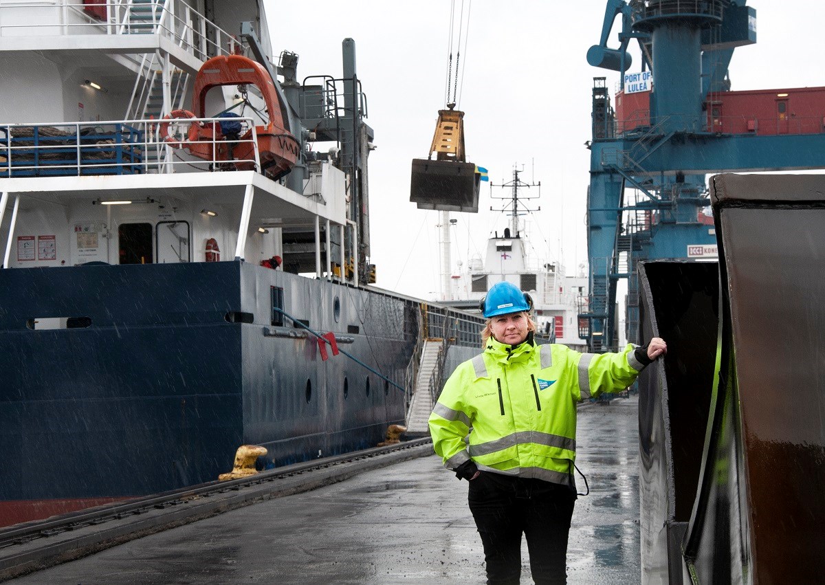 Linda Wikman står i Luleå hamn, hon har reflexgul jacka och en hjälm. Bakom hennes syns ett fartyg som blir lastat.