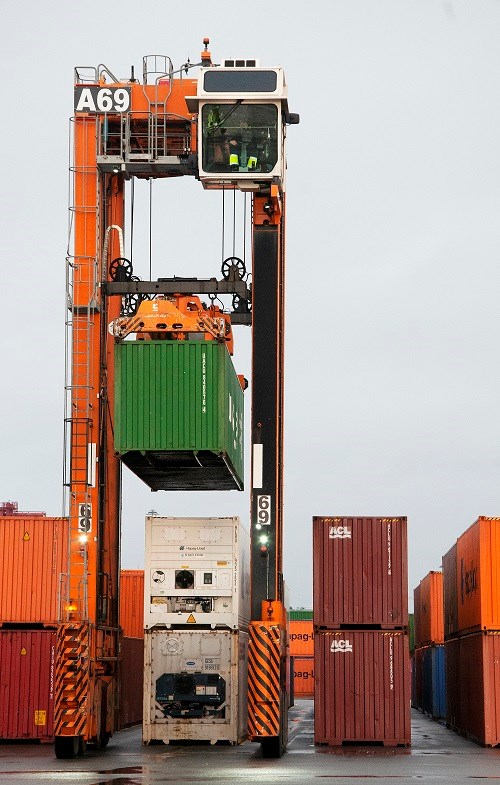 En gränsletruck lyfter en container i hamnen.