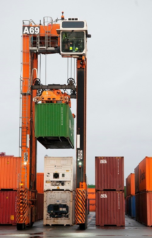 I Skandiahamnen finns 38 grensletruckar. Denna typ kan lyfta fyra containerhöjder och föraren sitter 12 meter ovan mark. Foto: Agne Hörnestig. En gränsletruck lyfter en container i hamnen.