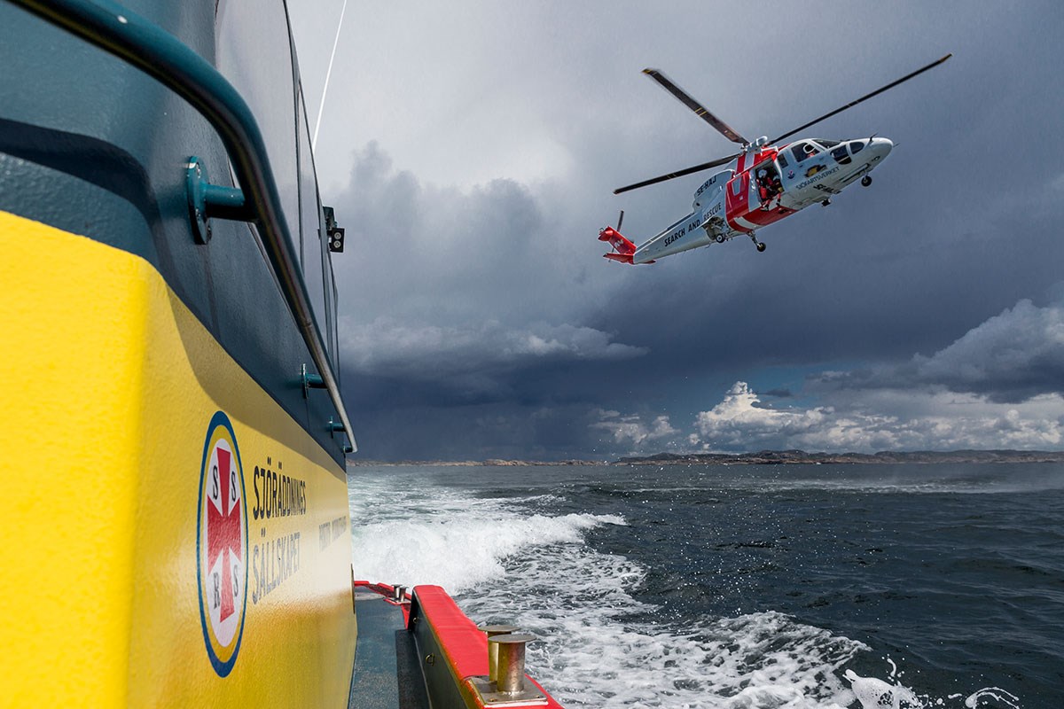 Grundstötningar och motorhaverier tillhörde några av de vanligaste larmorsakerna. Foto: Mats Ryde, Sjöräddningssällskapet En av Sjöräddningssällskapets båtar syns i förgrunden till vänster i bild, ovanför, till höger, flyger Sjöfartsverkets helikopter över havet.