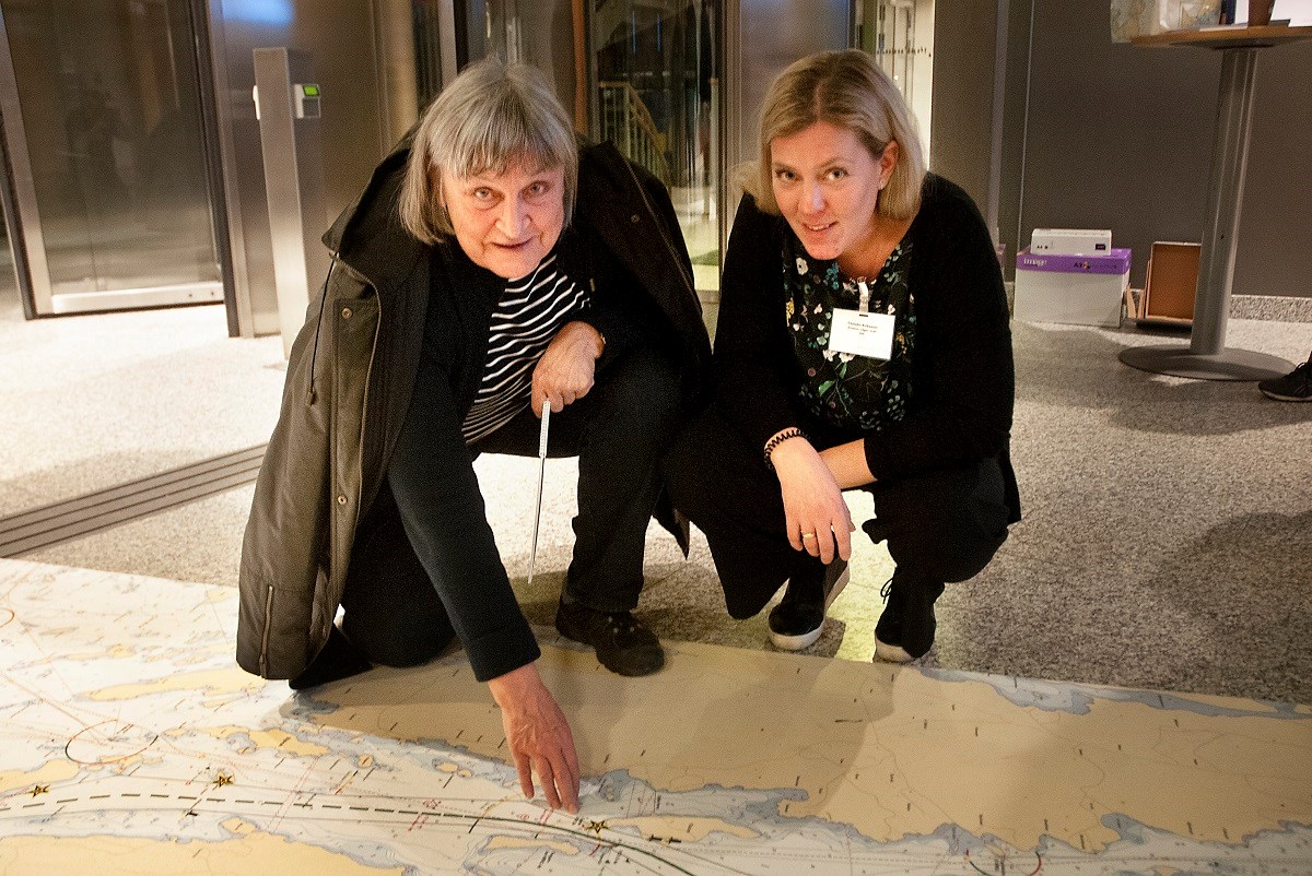 Elisabeth Karlsson, Oaxen, i samspråk med Christin Eriksson, ansvarig för frågor om erosion och svall. Foto: Agne Hörnestig Elisabeth Karlsson och Christin Eriksson sitter på huk över ett stort sjökort som ligger på golvet. De ser in i kameran och ler.