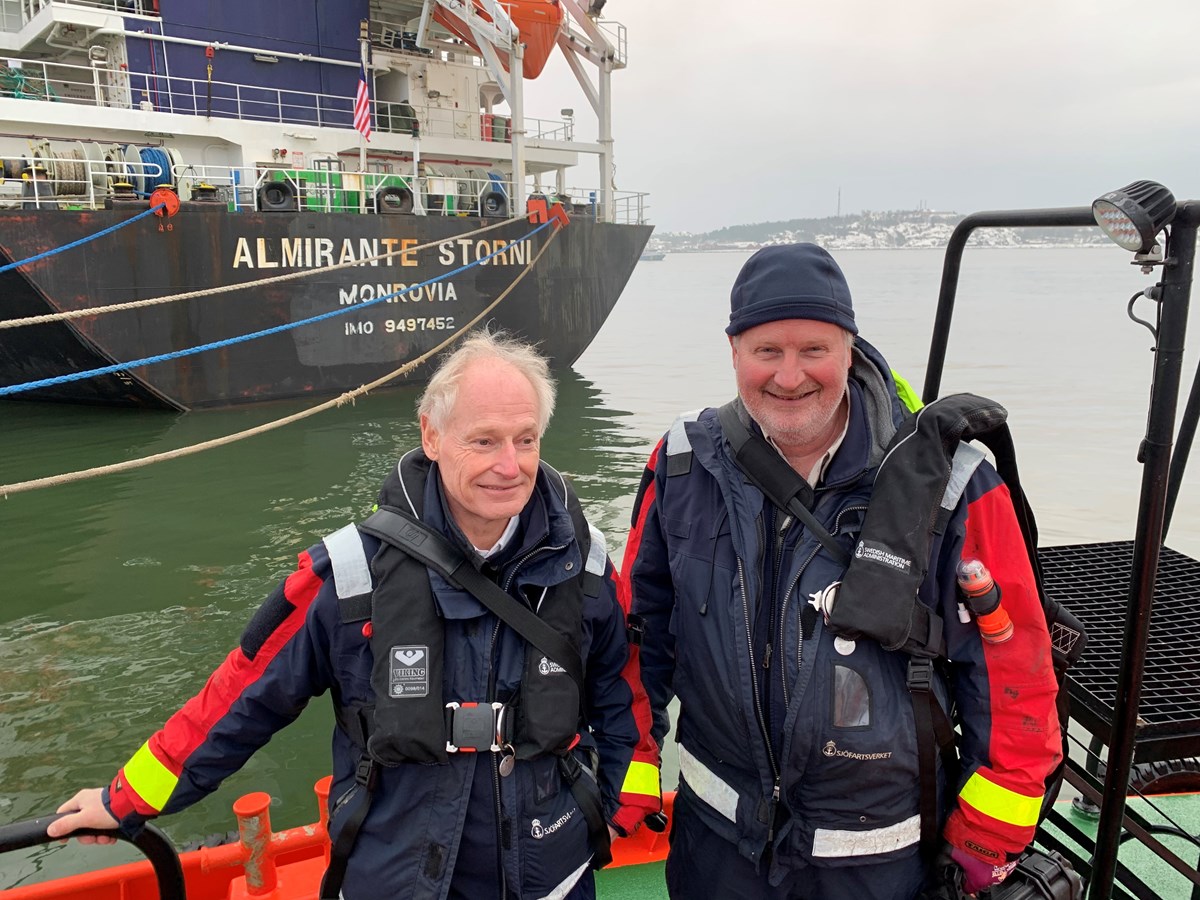 Henrik Sjöberg och Jonas Johansson Foto på två lotsar som tittar in i kameran. I bakgrunden syns fartyget Almirante Storni.