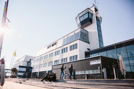 Högskolan sedd utifrån, med en klar och blank himmel och lite sol.