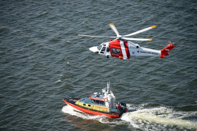helikopter flyger över vattnet. En räddningsbåt synds under. helikopter flyger över vattnet. En räddningsbåt synds under.