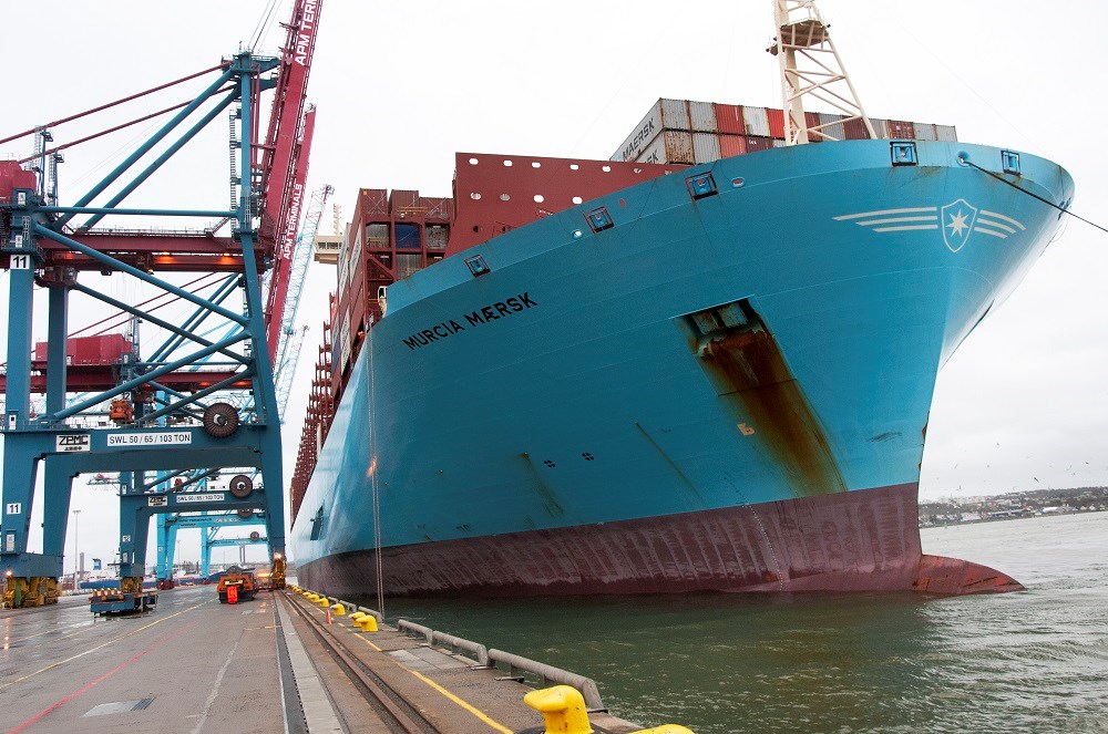 Ett stort fartyg ligger inne i Skandiahamnen. Över det syns kranar som lastar av containrar.