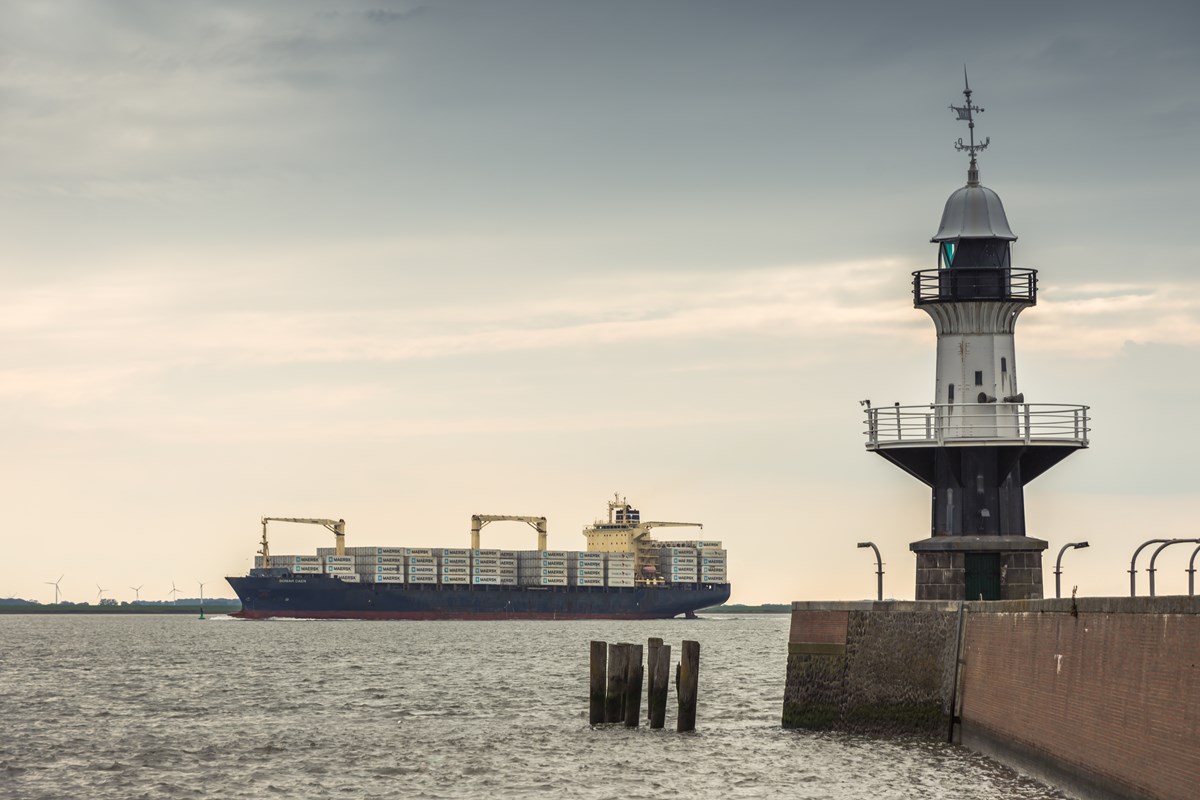 Ett fartyg syns på havet i bakgrunden med en fyr i förgrunden Ett fartyg syns på havet i bakgrunden med en fyr i förgrunden