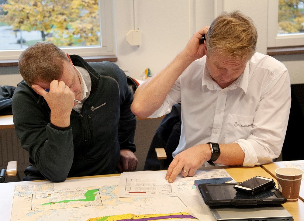 Stefan Nilsson och Magnus Lindgren utvärderar en av många körningar som gjorts i Sjöfartsverkets simulator. Foto: Agne Hörnestig. Stefan Nilsson och Magnus Lindgren sitter vid ett bord och ser ner i en karta. Båda kliar sig i huvudet.