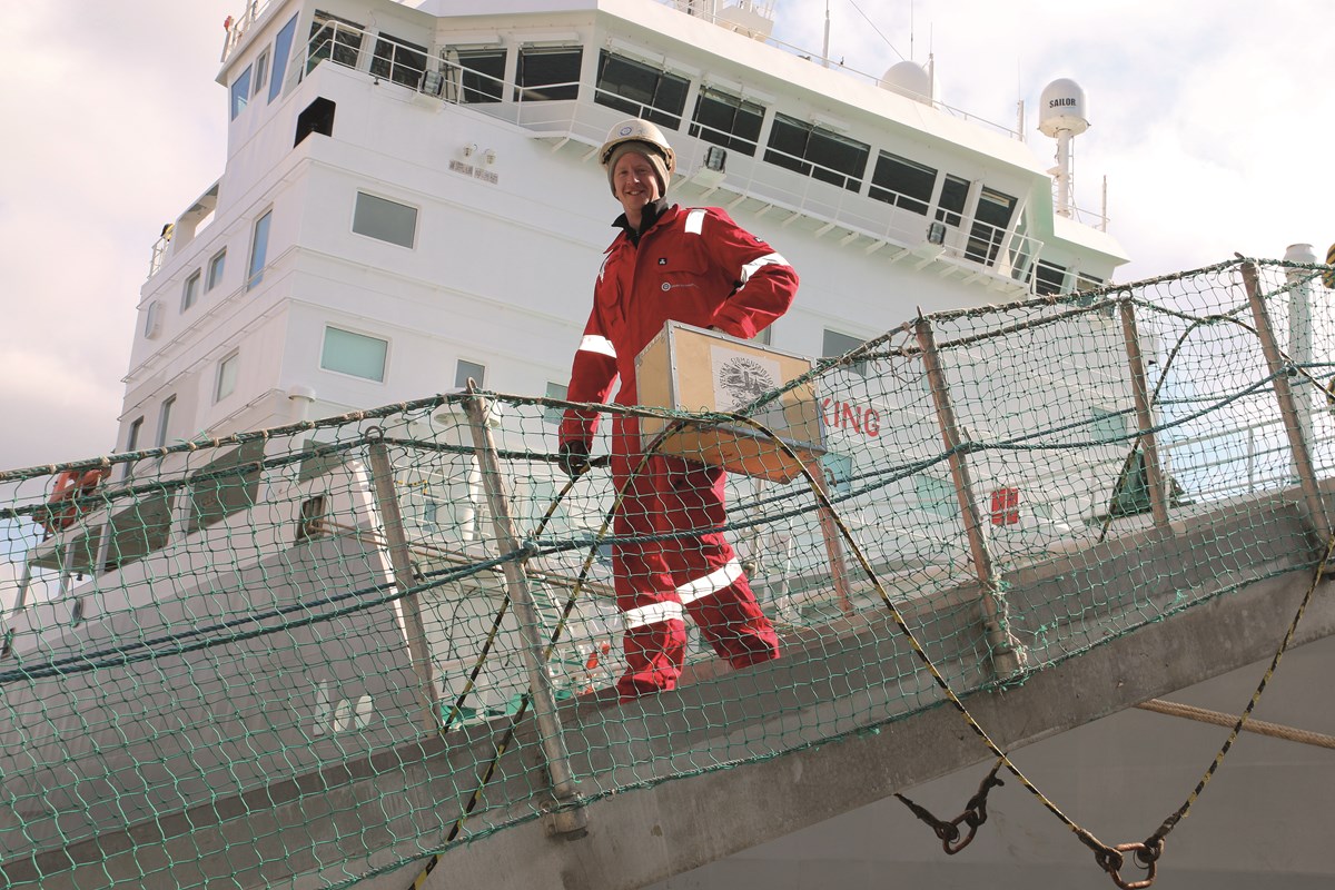 Sjömansservice medarbetare på väg med en låda underhållning. Från tidigare tillfälle. Foto: Glenn Hjelle Person med trälåda på väg mot fartyg.