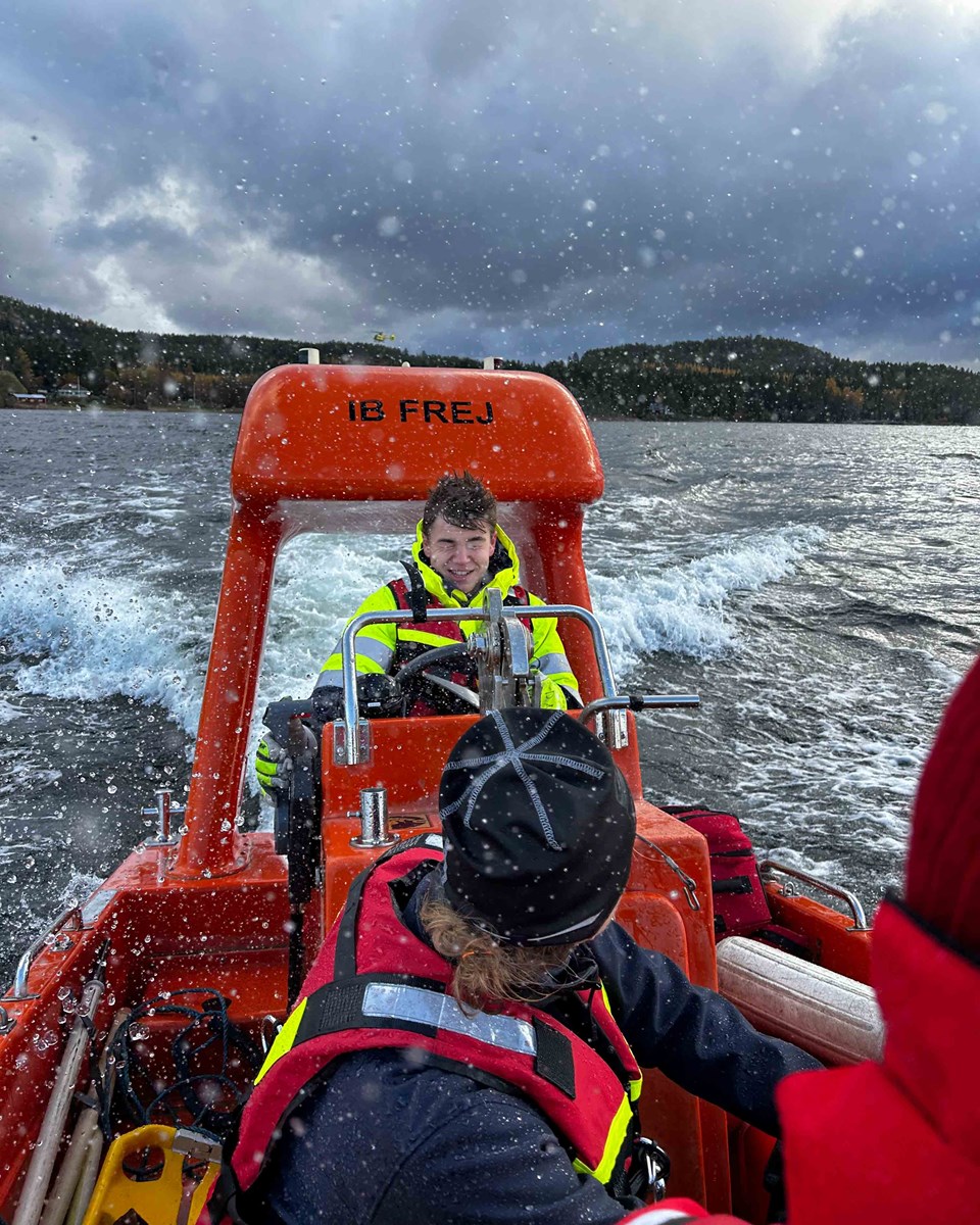Det gäller att älska sjön oavsett väder. Räddningsbåt, rufft väder, två personer, hav och himmel.