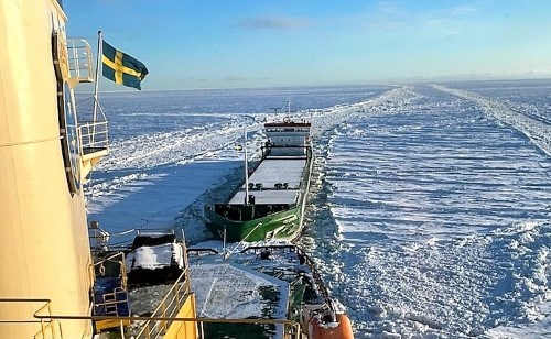 A vessel is escorted by an icebreaker.