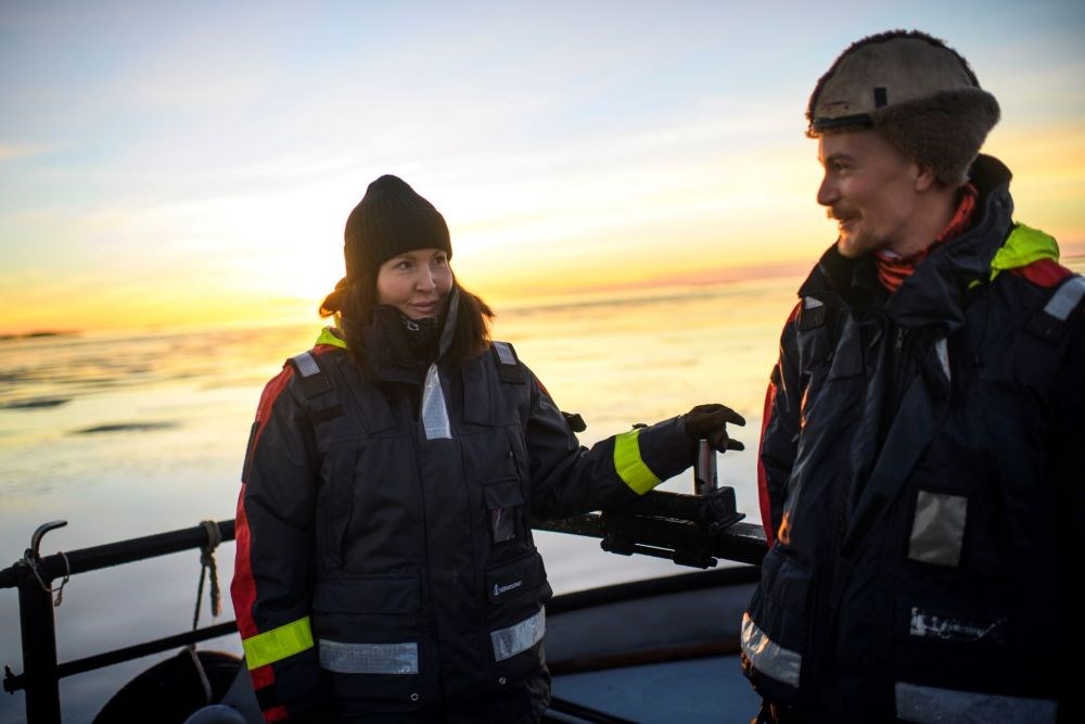 Lotta och Robert som tittar på varandra. I bakgrunden syns havet och en sol.