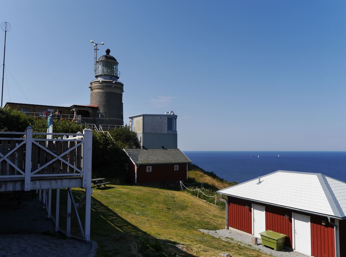 Bild på kullens fyr en fin sommardag med gräs och hus i förgrunden