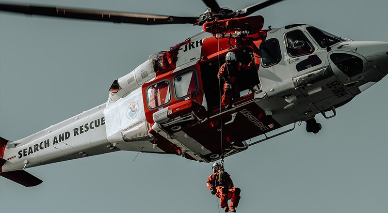 Bild på helikopter som vinschar en person.