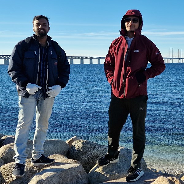 Två män står på en stenpir eller liknande och tittar in i kameran. I bakgrunden Öresundsbron Två män står på en stenpir eller liknande och tittar in i kameran. I bakgrunden Öresundsbron