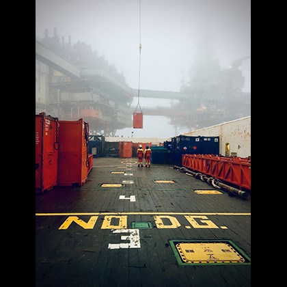 Two persons watching cargo being lifted at Valhall oil fied.