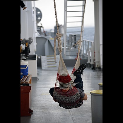 "Hanging out on deck" av Mikael Söderholm. En sjöman ligger i en hängmatta på däck.
