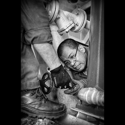 Man giving a helping hand to another man, working in a tight space
