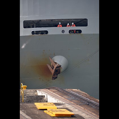 Three seafarers standing on board looking out at the docks