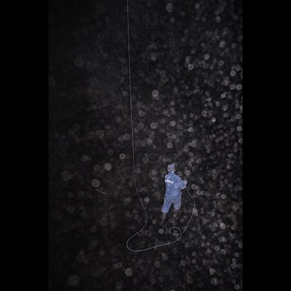 A seamen washing the inside of a large tank, diffusing drops of water in foreground.