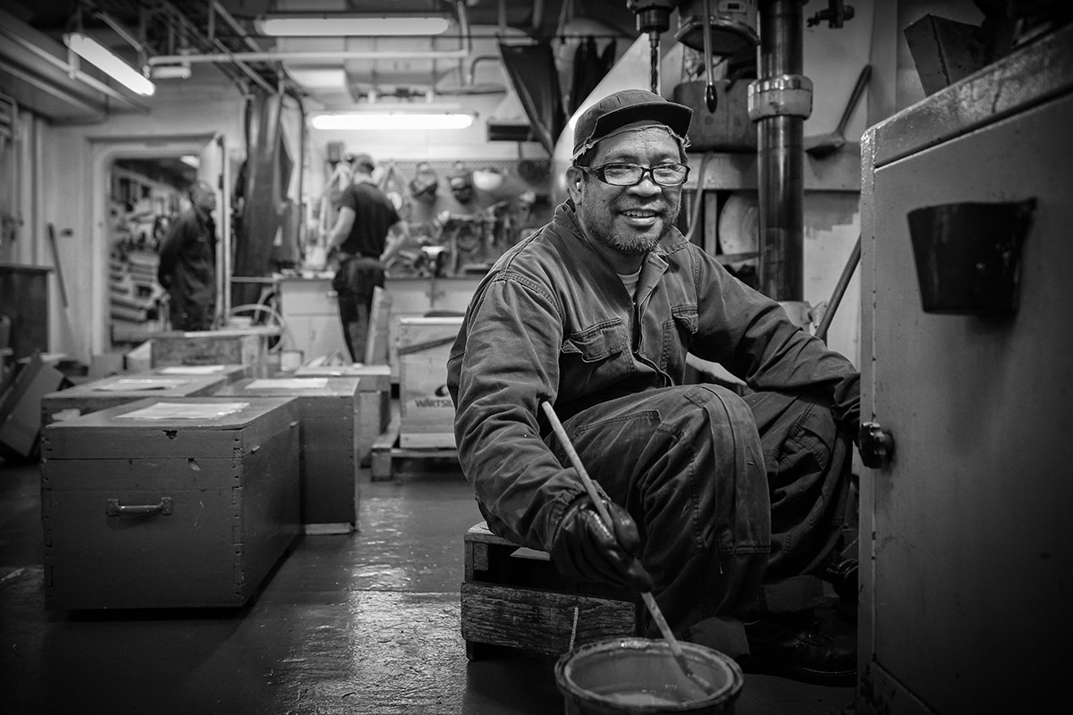 A smiling seafarer paints onboard