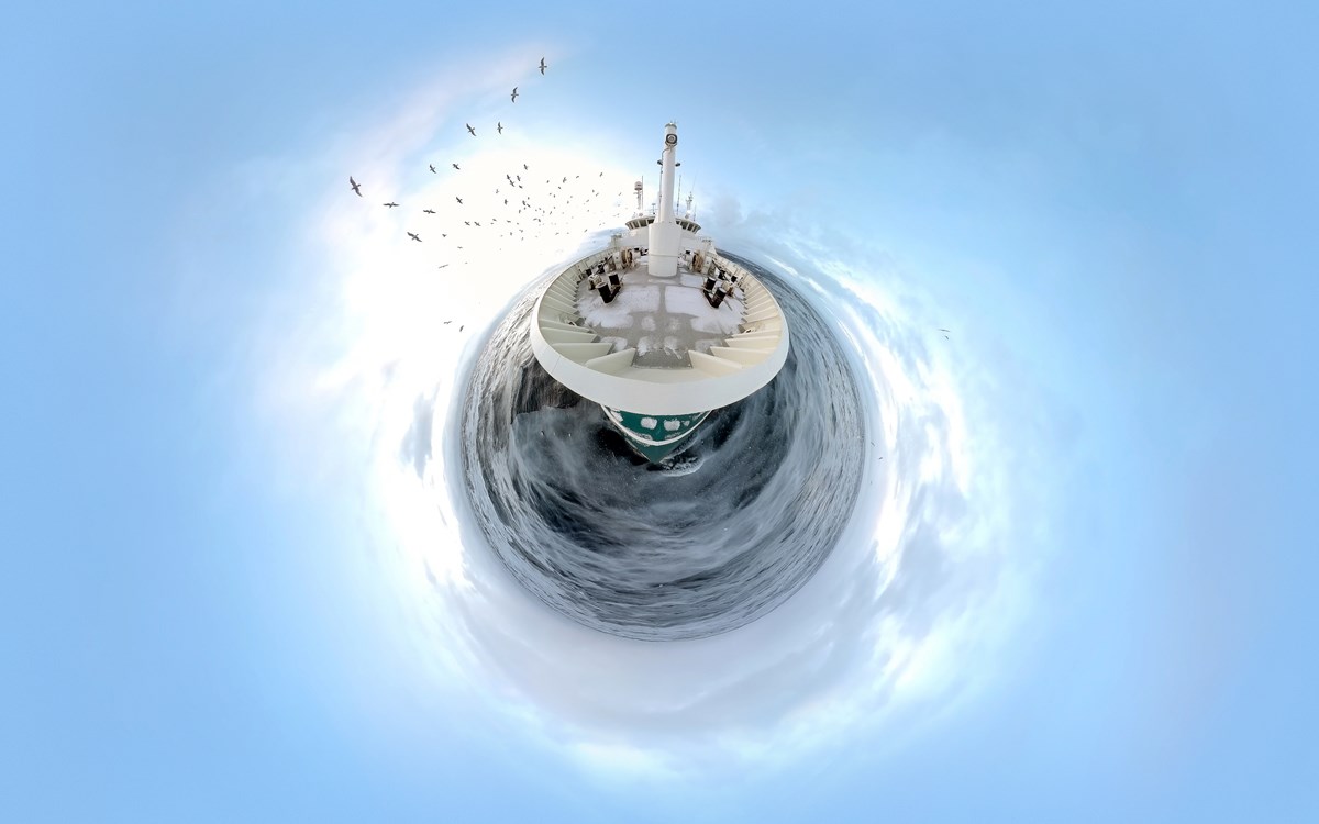 Fish-eye-bild från ovan på ett fartyg flankerat av fiskmåsar.