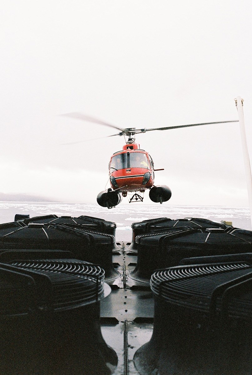 A helicopter is hovering over a ship deck