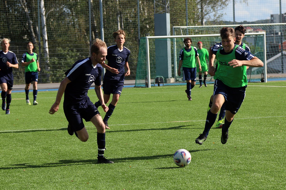 Donsötank i en åttondelsfinal mot tillresande Kalmarlaget Lambda FC. Vidare till kvarten gick Donsötankarna efter en seger med 2 mot 0. Två fotbollsspelare rusar mot bollen, en i blå dress och en i grön väst. I bakgrunden syns fler spelare.