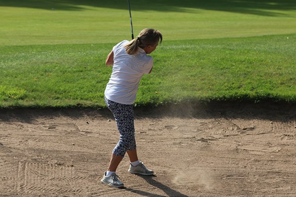 Golfspelare slår boll ur bunker