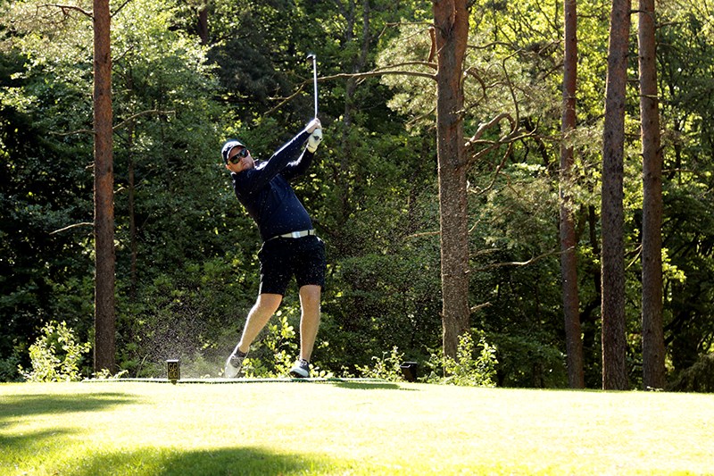 Golfare slår ut från tee. Sand flyger.