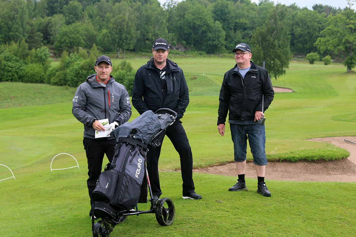 Tre golfare framför en bunker