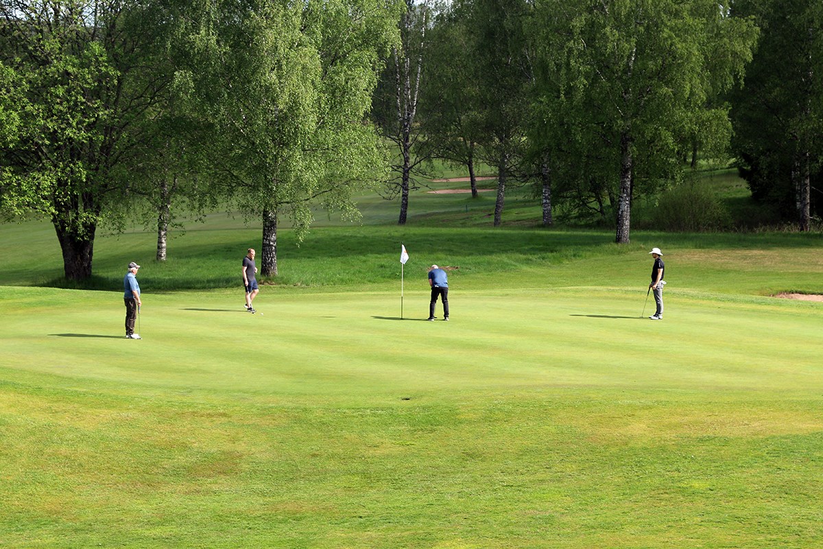 En spelare ska putta, tre tittar på, på avstånd