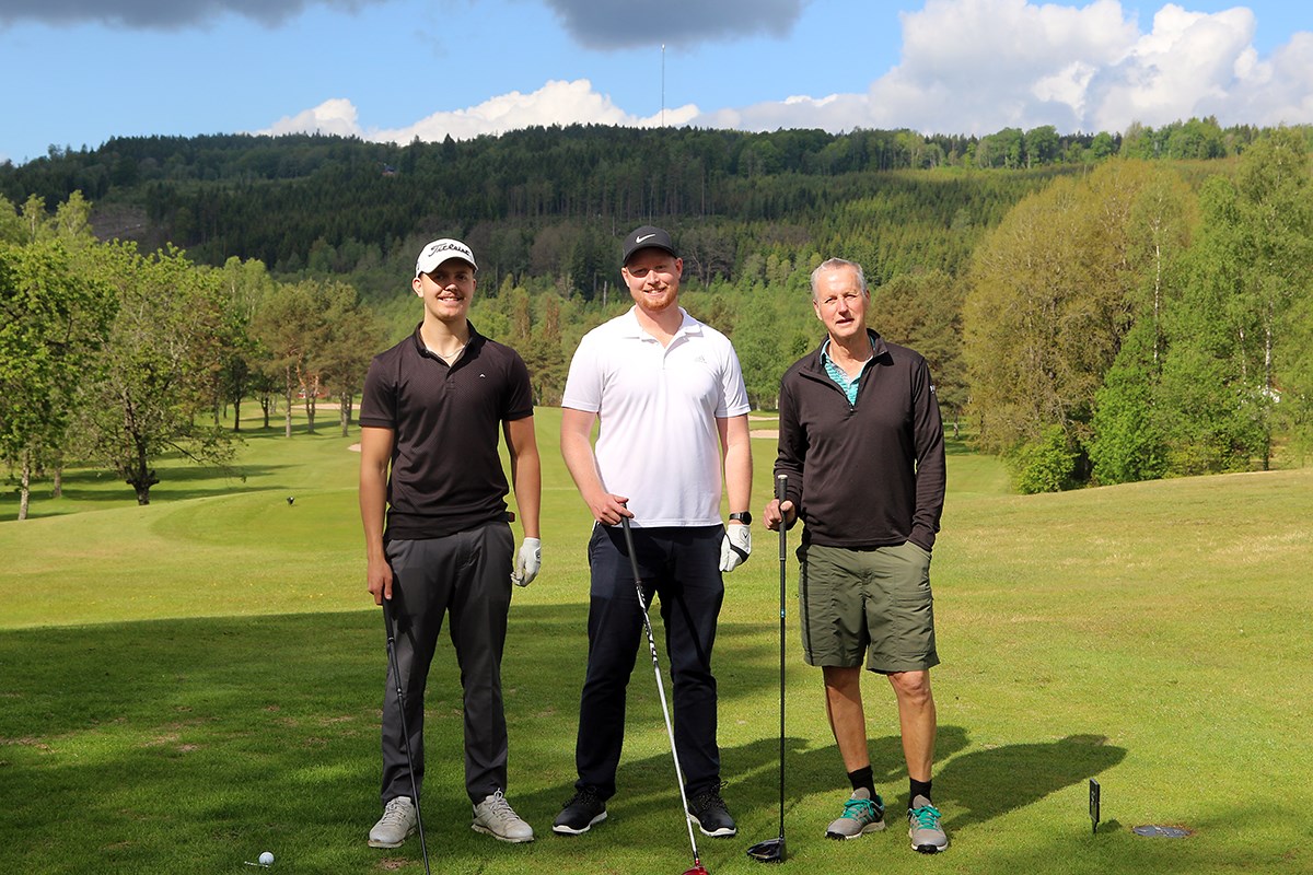 Tre golfspelare blickar mot kameran, inramade av grönska i olika nyanser