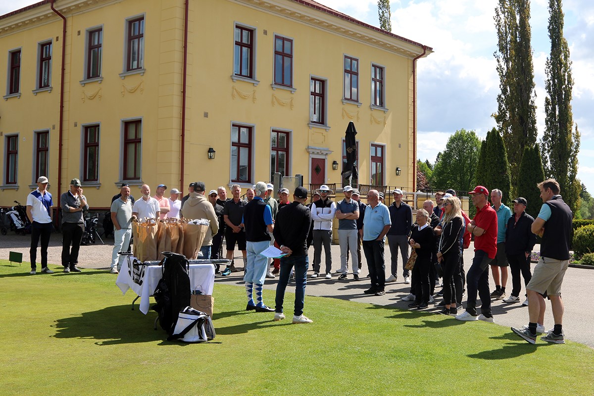Förväntansfull grupp på gräsmattan framför herrgårdsbyggnad, i väntan på prisutdelningen