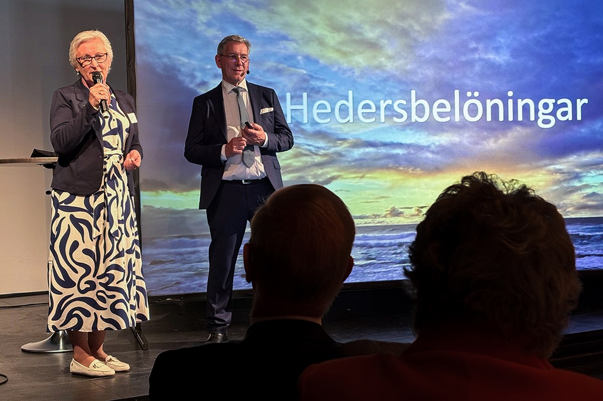 Agneta Swenson under sitt tacktal. Stiftelsens kanslichef Karl Karell till höger. En kvinna och en man står på scenen, på den stora projektorduken i bakgrunden står det Hedersbelöningar